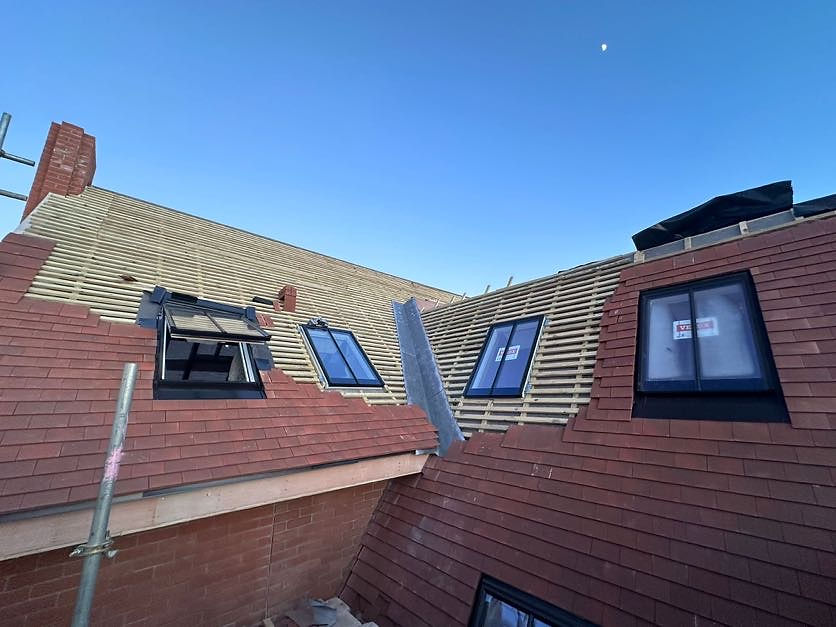 Roof under construction with red tiles and skylights