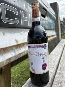 Blackberry wine on a bench outdoors.