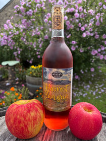 Harvest Sangria bottle of wine in front of flowers with apples on a table.