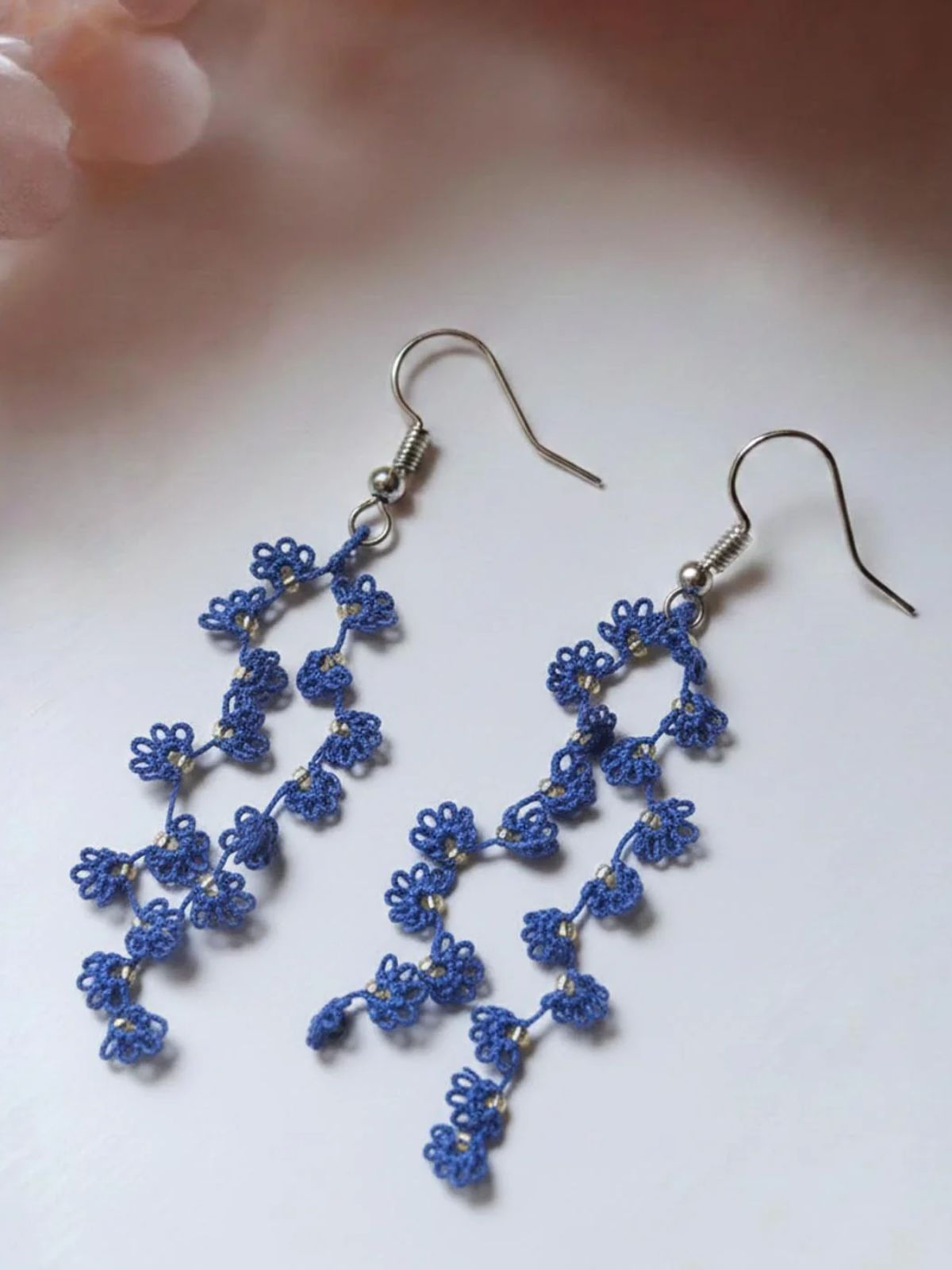 Navy vine trail handmade tatting earrings by Knots to Node with silver hooks on a light neutral background