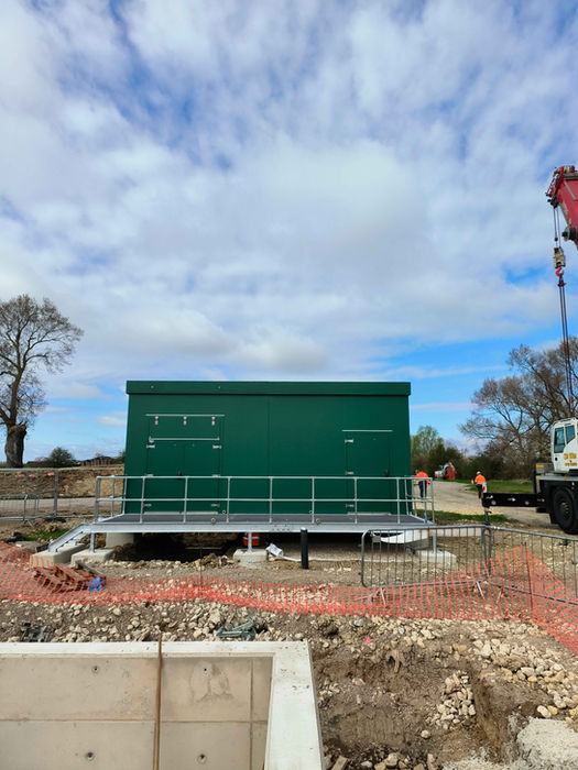 Green GRP substation kiosk and the access platform in front of it.