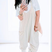 The Airport Arrival: A woman in a light beige FP Movement onesie over a white t-shirt, wearing white boots and taking a mirror selfie.