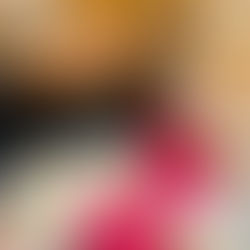 A white oval plate featuring two thick slices of golden-brown brioche French toast, topped with melted butter and syrup. The plate is beautifully styled with a heap of fresh raspberries, blackberries, and sliced bananas. On the side are crispy shredded hash browns and a strip of turkey bacon, set against a neutral, rustic background.