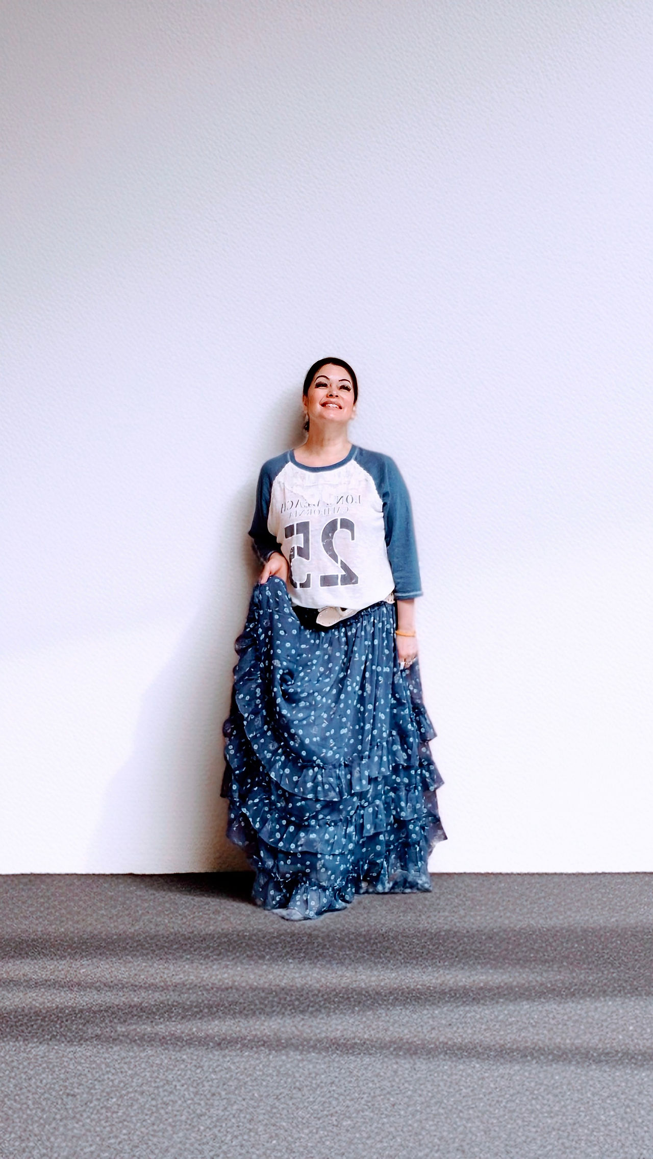 A high-low texture mix featuring a vintage-style baseball graphic tee paired with a voluminous, tiered blue floral maxi skirt.