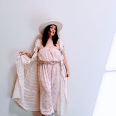 A Boho-Western look featuring a floral print jumpsuit and a long, flowing lace duster coat, styled with a wide-brim white hat and lavender boots.