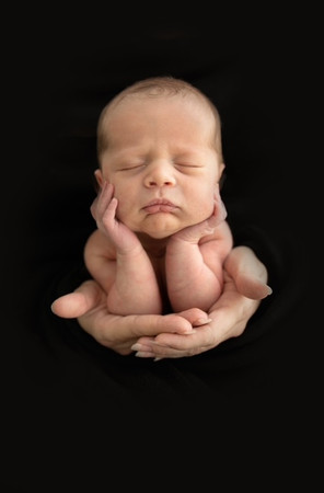 Newborn posed safely in the froggy position supported by parents’ hands during a session with Suzi Brown Photography