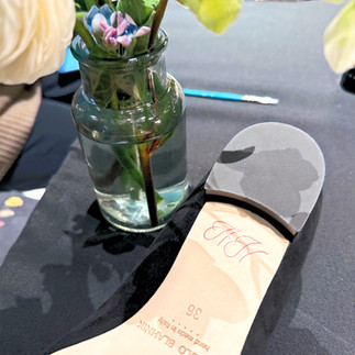 Bottom of Manolo Blahnik shoe with HH calligraphed in light pink, sitting on a black tale clot