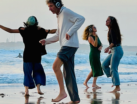 Dancers with wireless headphones at Playa de la Barrosa during sunset
