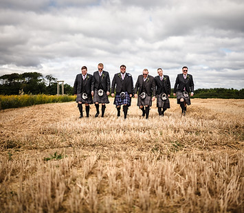 Groom & Groomsmen walking in bridal dress in a cornfield.