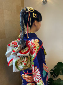 青い振袖に白い帯を結んだ新成人の後ろ姿