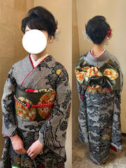 黒い総絞りの振袖に赤い小物を合わせて着る新成人