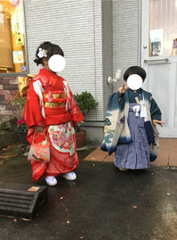 七五三のお祝いで赤の着物を着て、お団子ツインの髪形をした5歳の女の子と青い袴を着た3歳の男の子