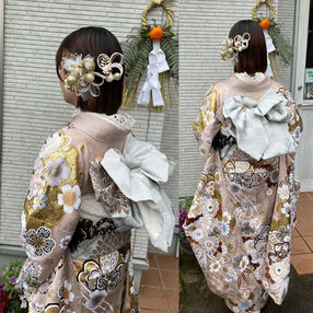 ピンクの振袖に白い帯を締め、ショートのダウンスタイルに水引や花の髪飾りを付けた新成人