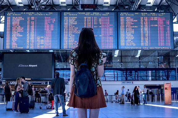 Voyageuse avec sac à dos consultant le tableau des départs dans un aéroport.