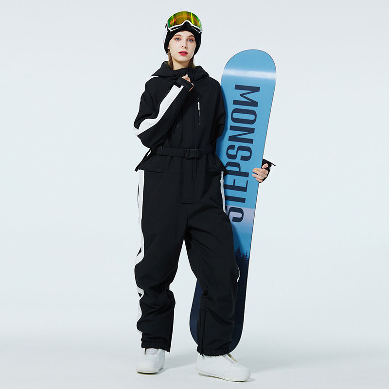 サムネイル： 女性がステップスノーのボードを持ち、黒い防寒着を着て立っています。STEPSSNOW の文字が目立つ