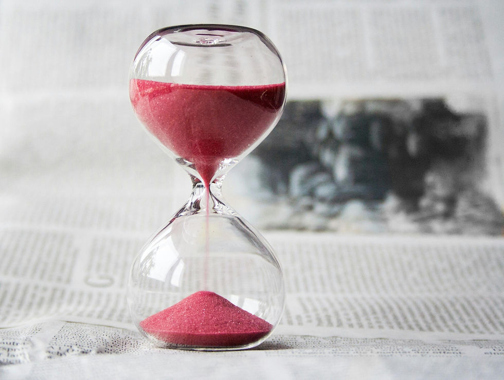 An hourglass on a newspaper, with pink sand halfway through the narrow neck, symbolizing the concept of passing time.