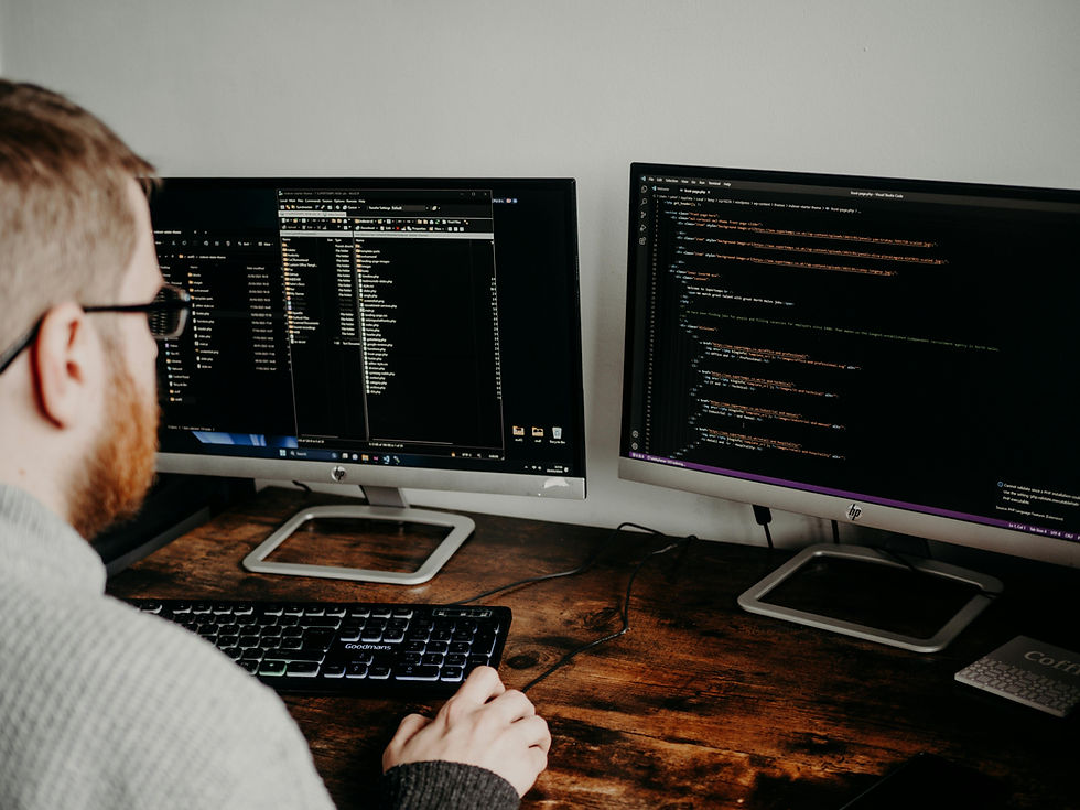 A developer working on two large monitors displaying lines of code. The focus is on code development and programming in an office environment.