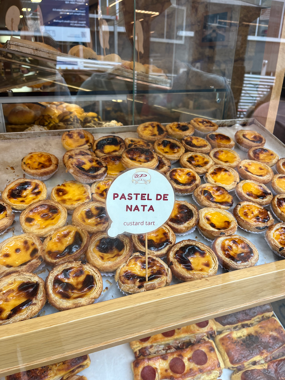 Fresh pastel de nata displayed in a bakery window in Porto, Portugal.