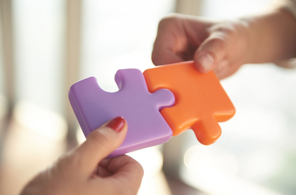 Two people fitting two puzzle pieces together