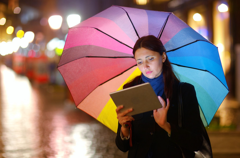 Women holding an umbrella while using an ipad outside while raining
