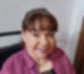 Me smiling at the camera at a slight angle and wearing a purple blouse with white spots.