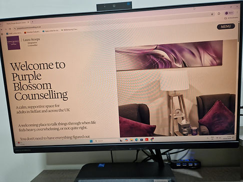 A desktop computer with the Purple Blossom Counselling website homepage on screen.