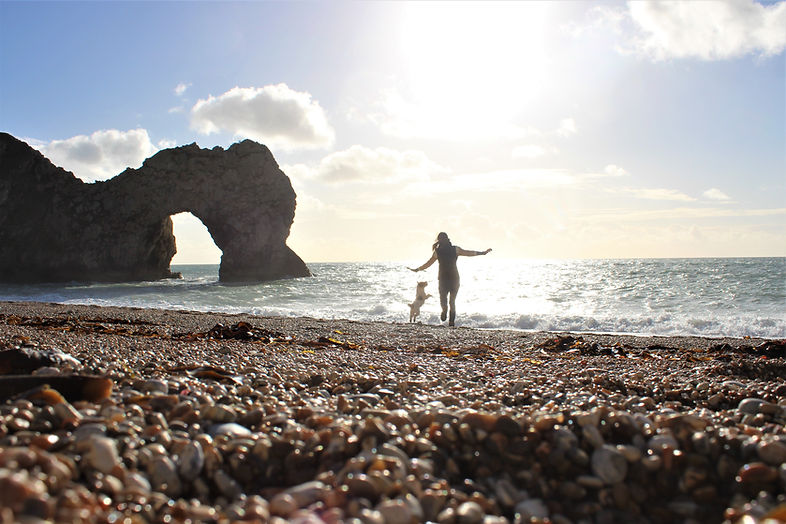 Girl and dog on beach Dorset durdle door sunshine silhouette