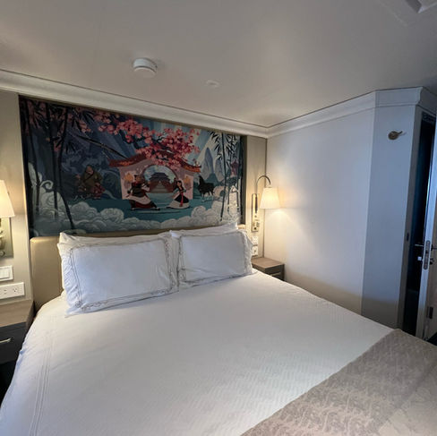 Cruise ship cabin with Mulan wall art above the bed.