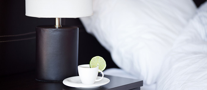 A cosy bedside view at Brezza Hotel Lumut with soft pillows, a warm lamp, and a cup of tea for a relaxing stay