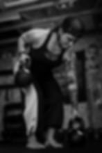 Liz M bent over using kettle bells in a workout with a focused look on her face