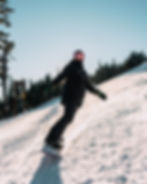 A snowboarder wearing all black on a sunny days in the mountain