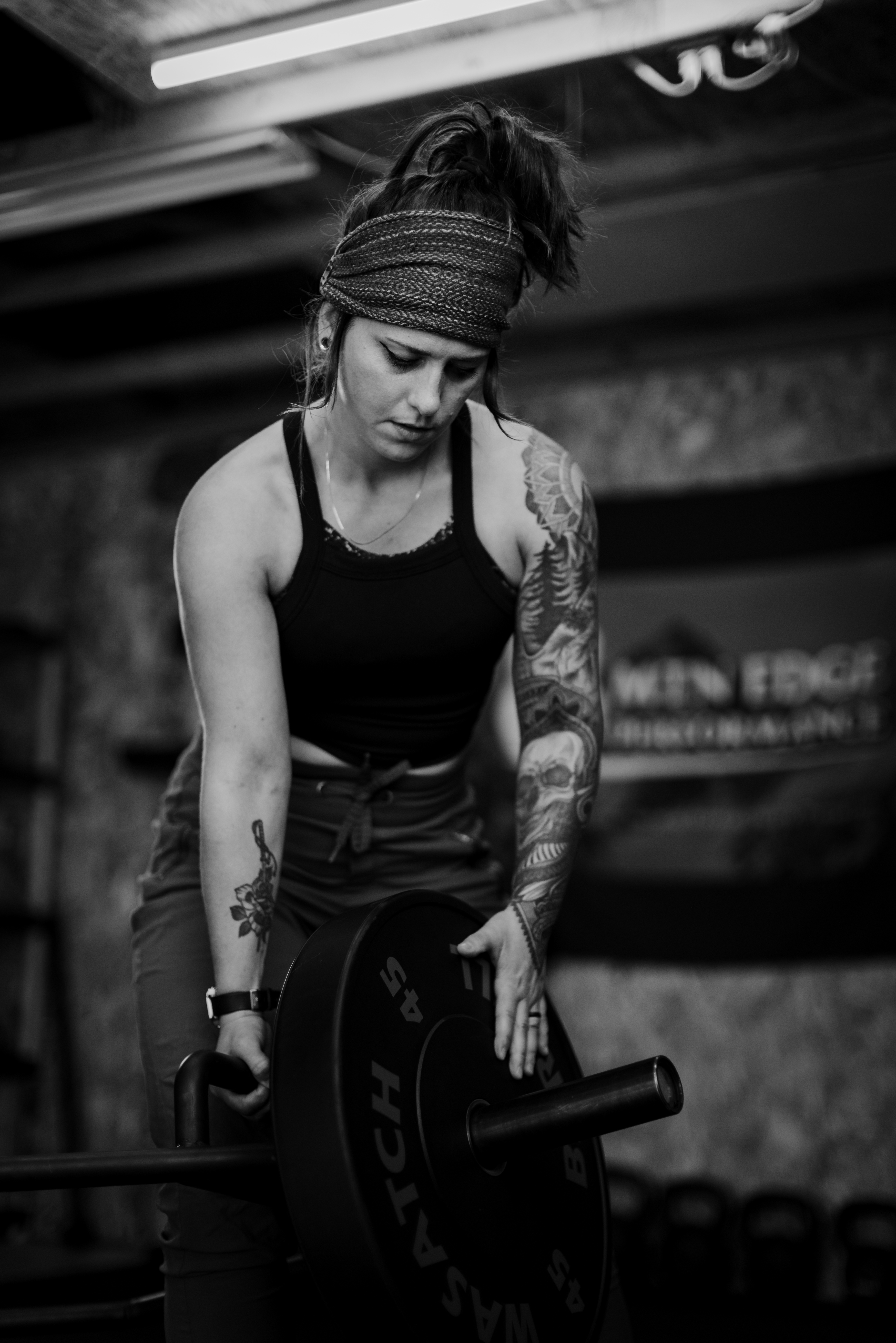 Liz of mountain edge performance putting plates onto a bar at her home gym