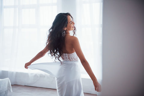 from-beautiful-woman-white-dress-stands-white-room-with-daylight-through-windows.jpg