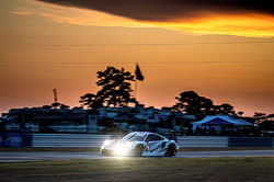 Porsche rounding a turn at sunset.