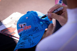 Driver signing a fans hat.