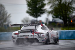 Porsche racing around a turn in the rain_