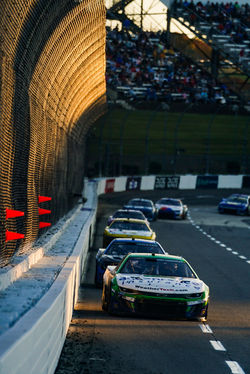 Camaro rounding a turn seen through the chain link fencing.