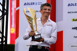 Crew chief holding trophy on the podium.