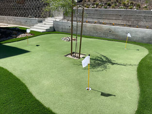 Synthetic turf putting green installation with golf holes and landscaped surroundings.