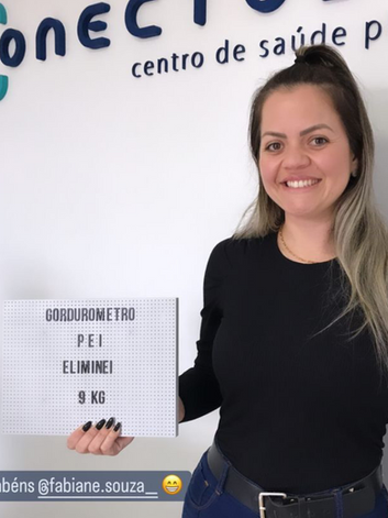 Fabiana segurando sua placa com o resultado de finalizar o programa de emagrecimento integrativo.