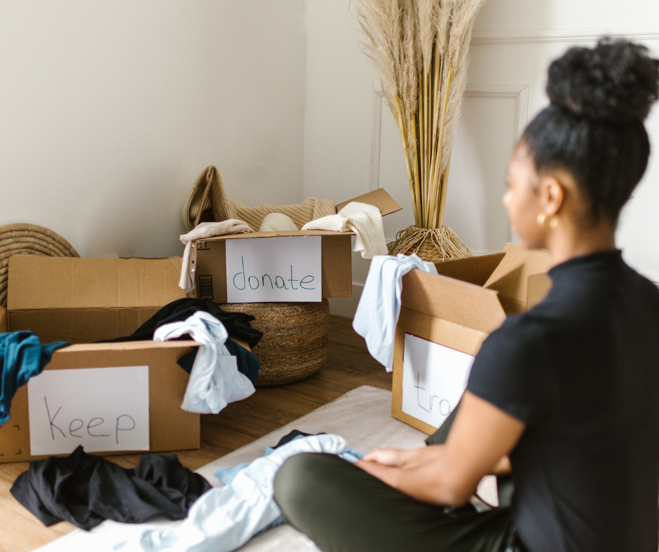 A mom sitting in front of three boxes, labeled Keep, Donate, and Trash, representing the stress of seasonal organizing when you try to do it all.