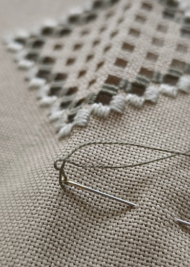 ouvrage broderie, fils vert et tissu en lin beige