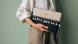 femme portant pochette bohème bi matière et couleurs (toile de jute noir et tissu coton doré) orné franges. Fait main .