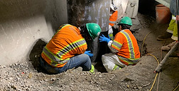Three construction workers ensuring proper placement of a support beam.
