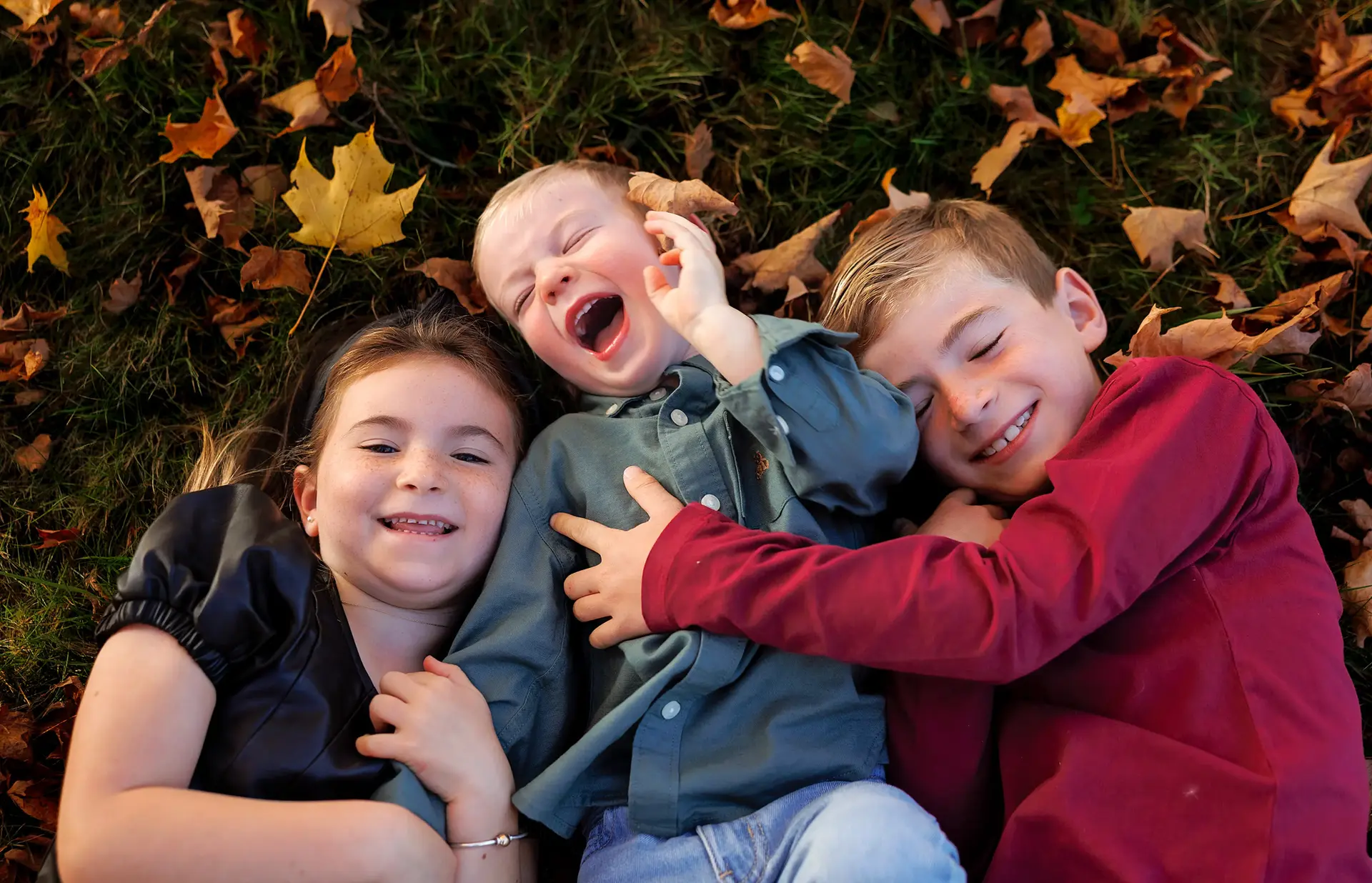 leaves on the ground, kids laying in the leaves, laughing