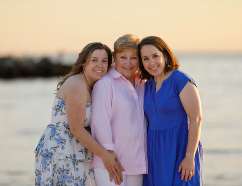 Mother and adult daughters smiling together, embracing and enjoying a joyful moment outdoors. cape cod photographers