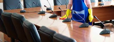 woman cleaning a desk in conference room