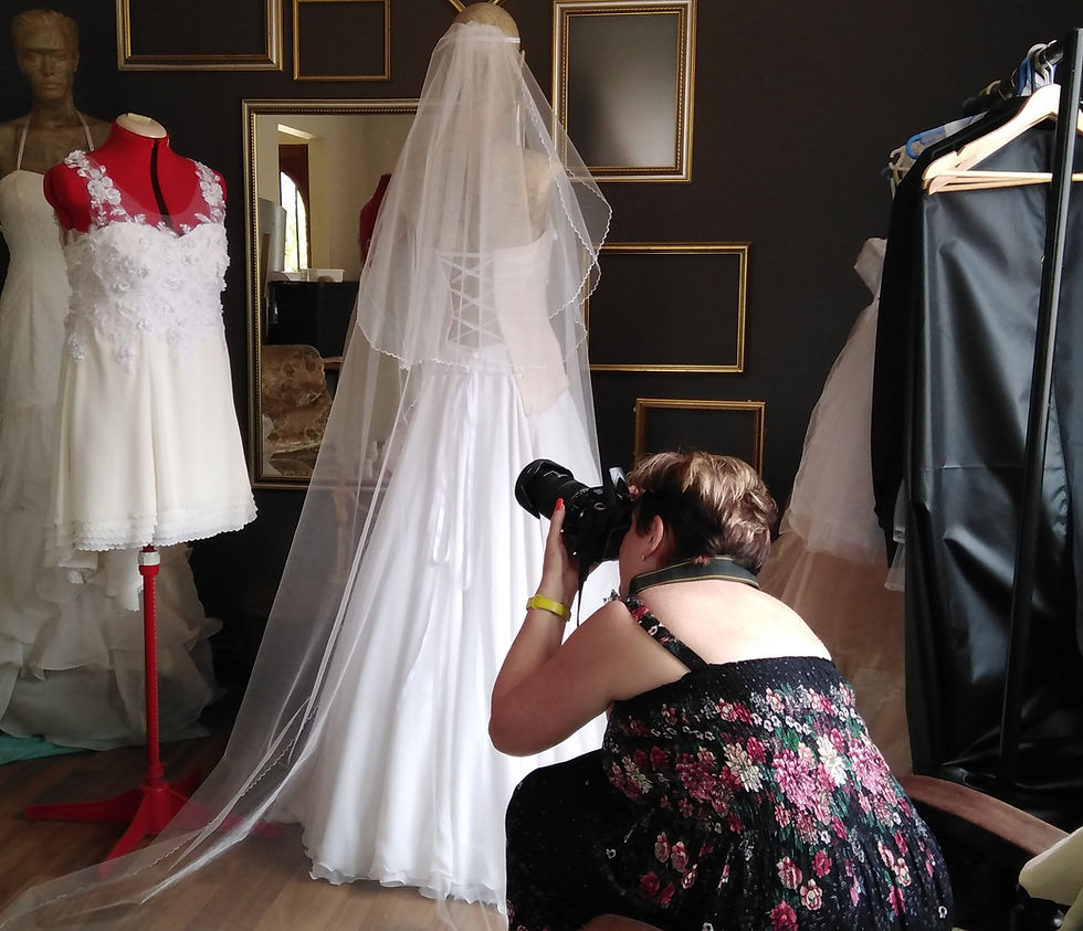A photographer is taking pictures of wedding dresses at an angle from below which is displayed on a mannequin