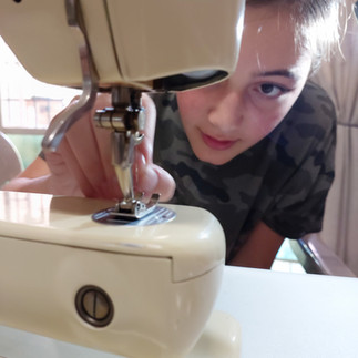 A girl trying to thread the needle on her sewing machine