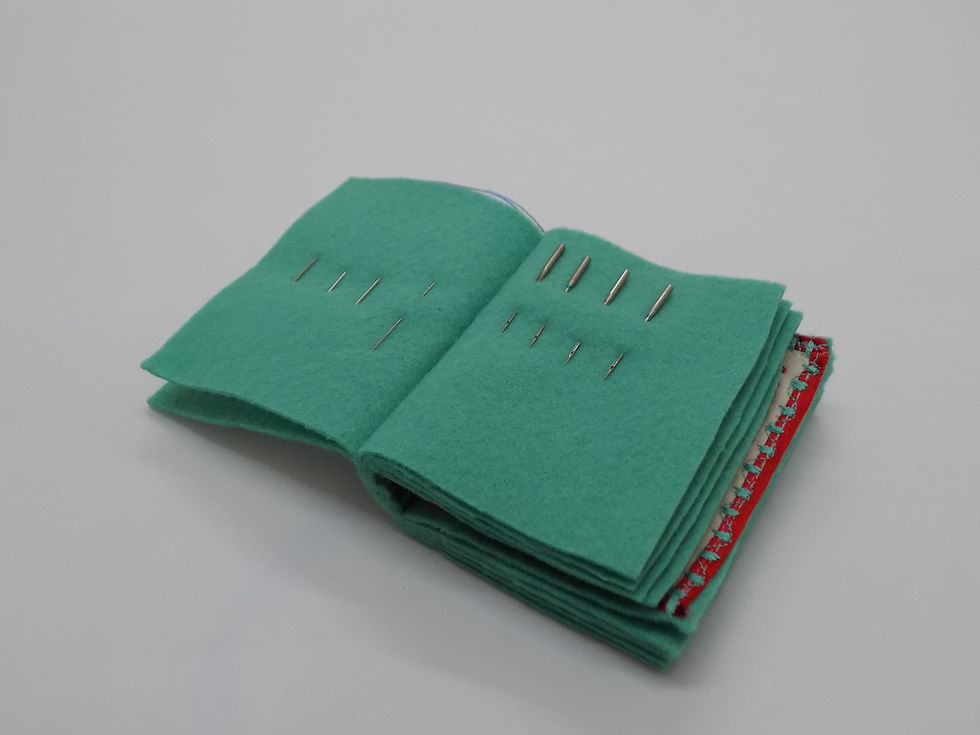 High angle view of a completed green felt needle booklet resting on a wooden table